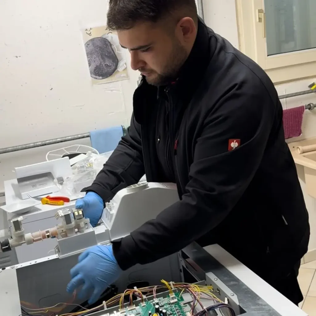 Mitarbeiter der SwissTech Service AG repariert eine Waschmaschine – professioneller Haushaltsgeräte Reparaturservice.